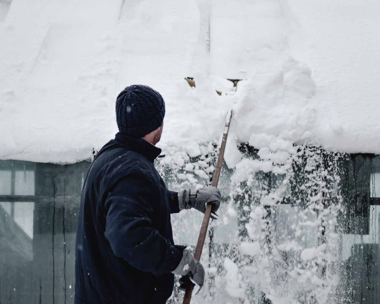 Man using a snow rake on his roof